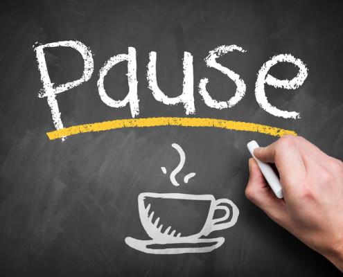 The word PAUSE written on a chalkboard with the picture of a coffee cup below