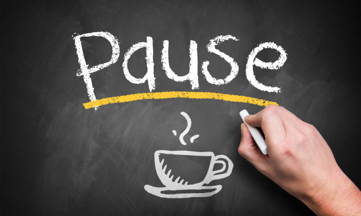 The word PAUSE written on a chalkboard with the picture of a coffee cup below